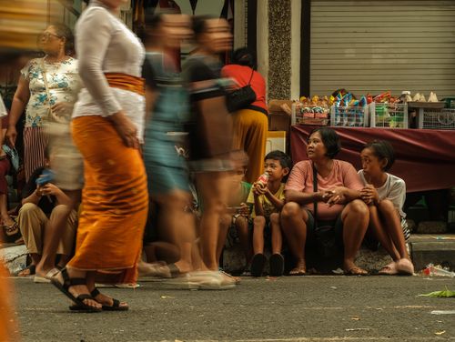 Free A candid street scene capturing people sitting and walking near market stalls. Stock Photo