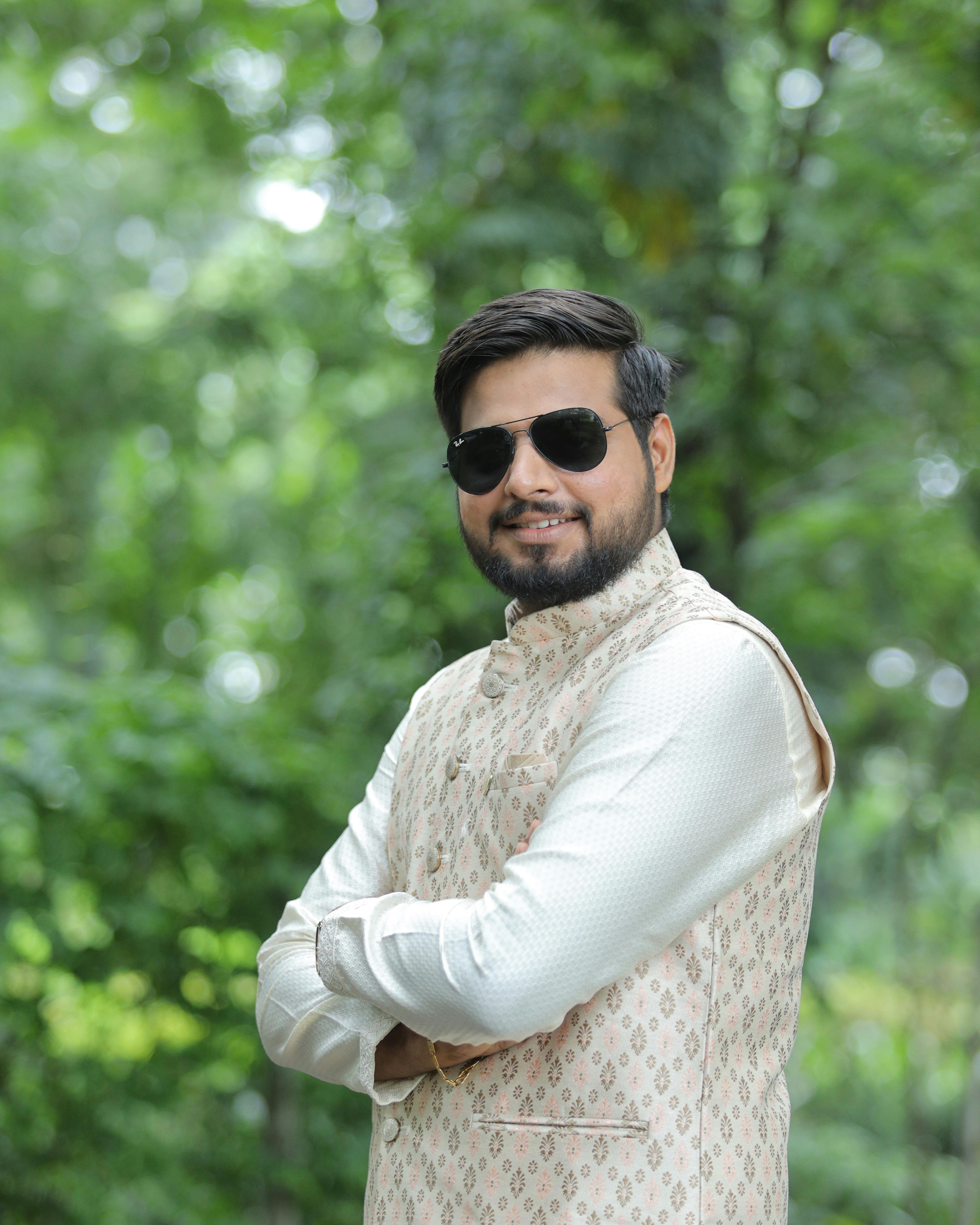 Portrait of a confident man wearing sunglasses and a traditional kurta outdoors, exuding style and grace.