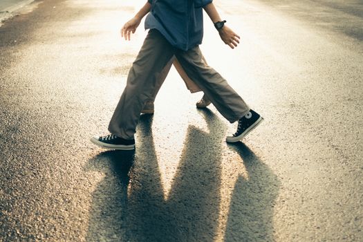 Two people cross paths casting long shadows on a sunlit street in Cirebon.
