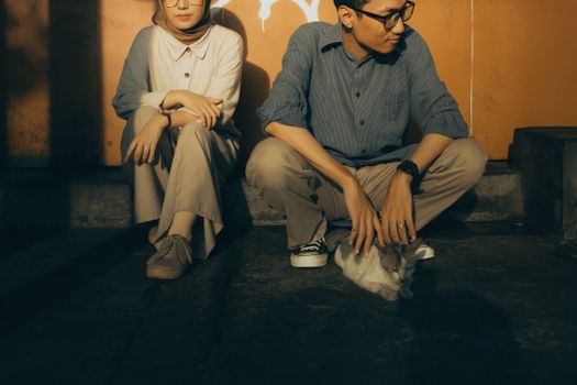 A serene moment of a couple sitting outdoors with a cat, enjoying a casual atmosphere.