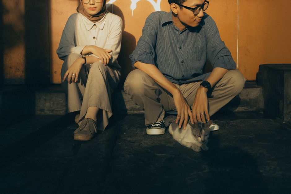 A serene moment of a couple sitting outdoors with a cat, enjoying a casual atmosphere.