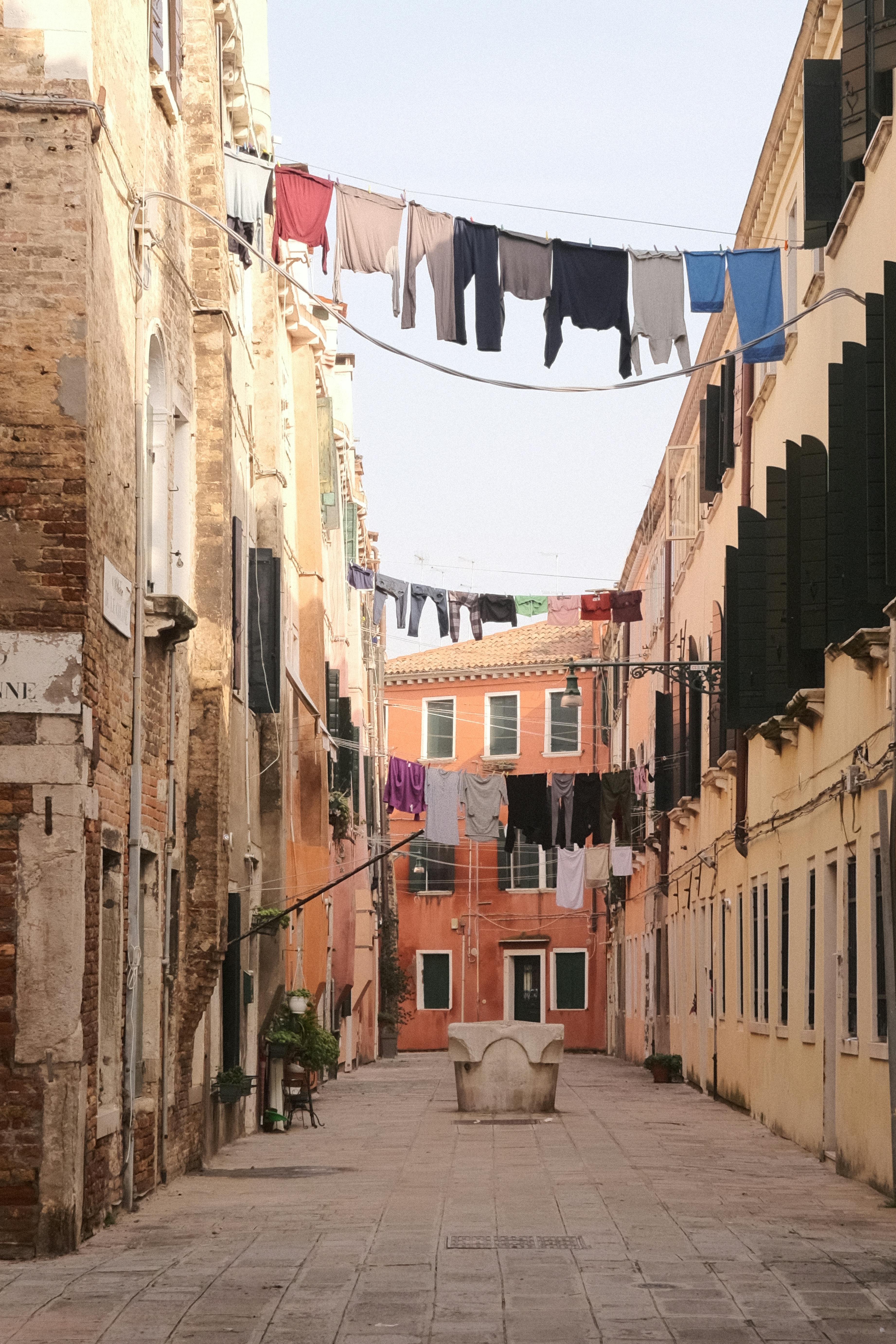 бесплатная Спокойная уличная сцена в Венеции, Италия, где развешенное белье находится между деревенскими постройками. Стоковое фото