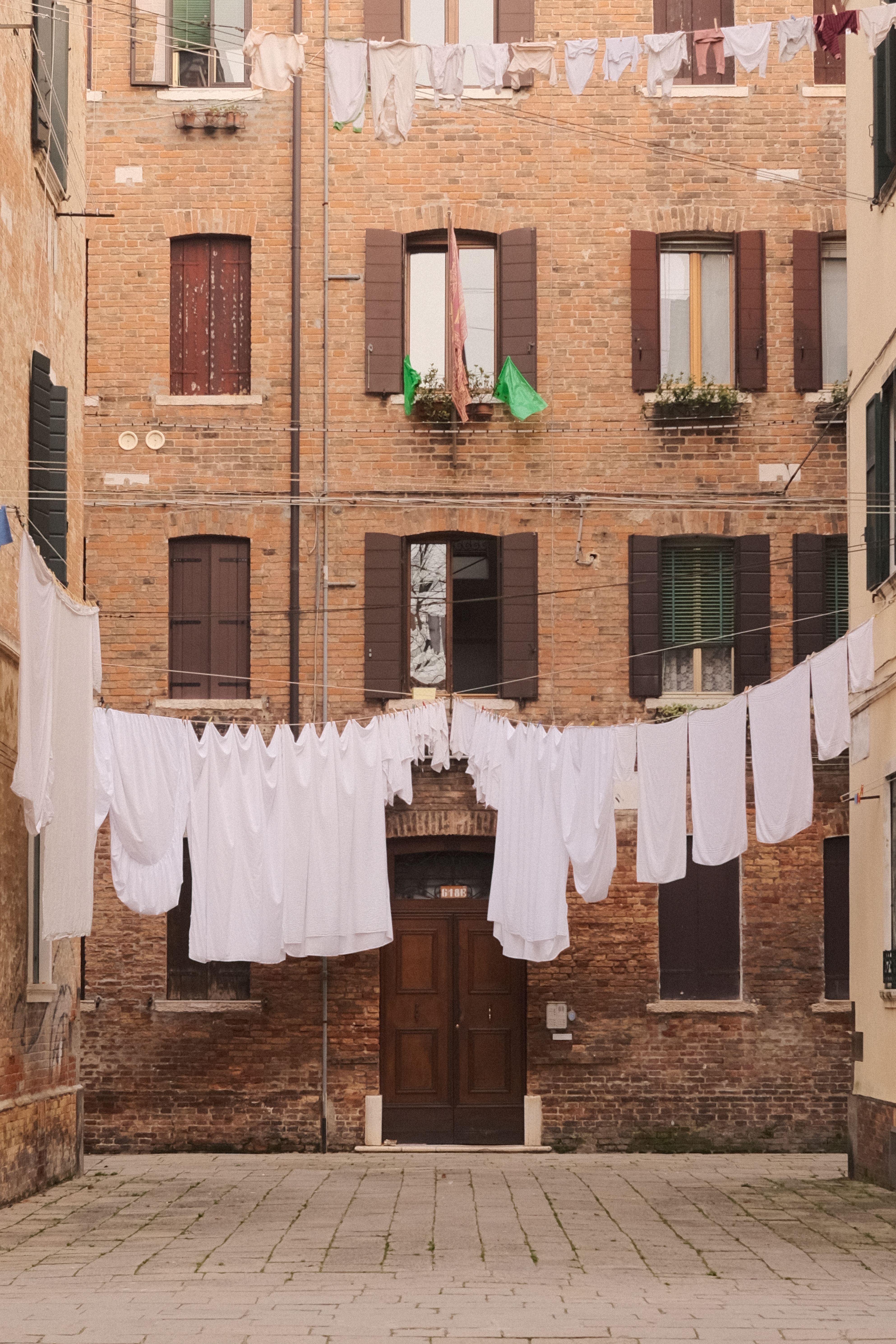 A quaint Venetian courtyard with traditional brick buildings and hanging laundry.