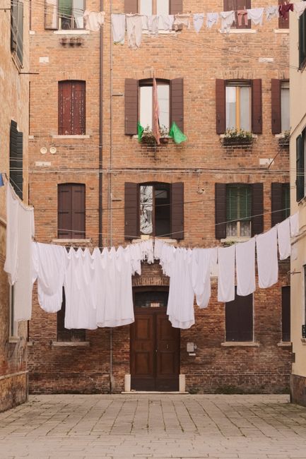 A quaint Venetian courtyard with traditional brick buildings and hanging laundry.