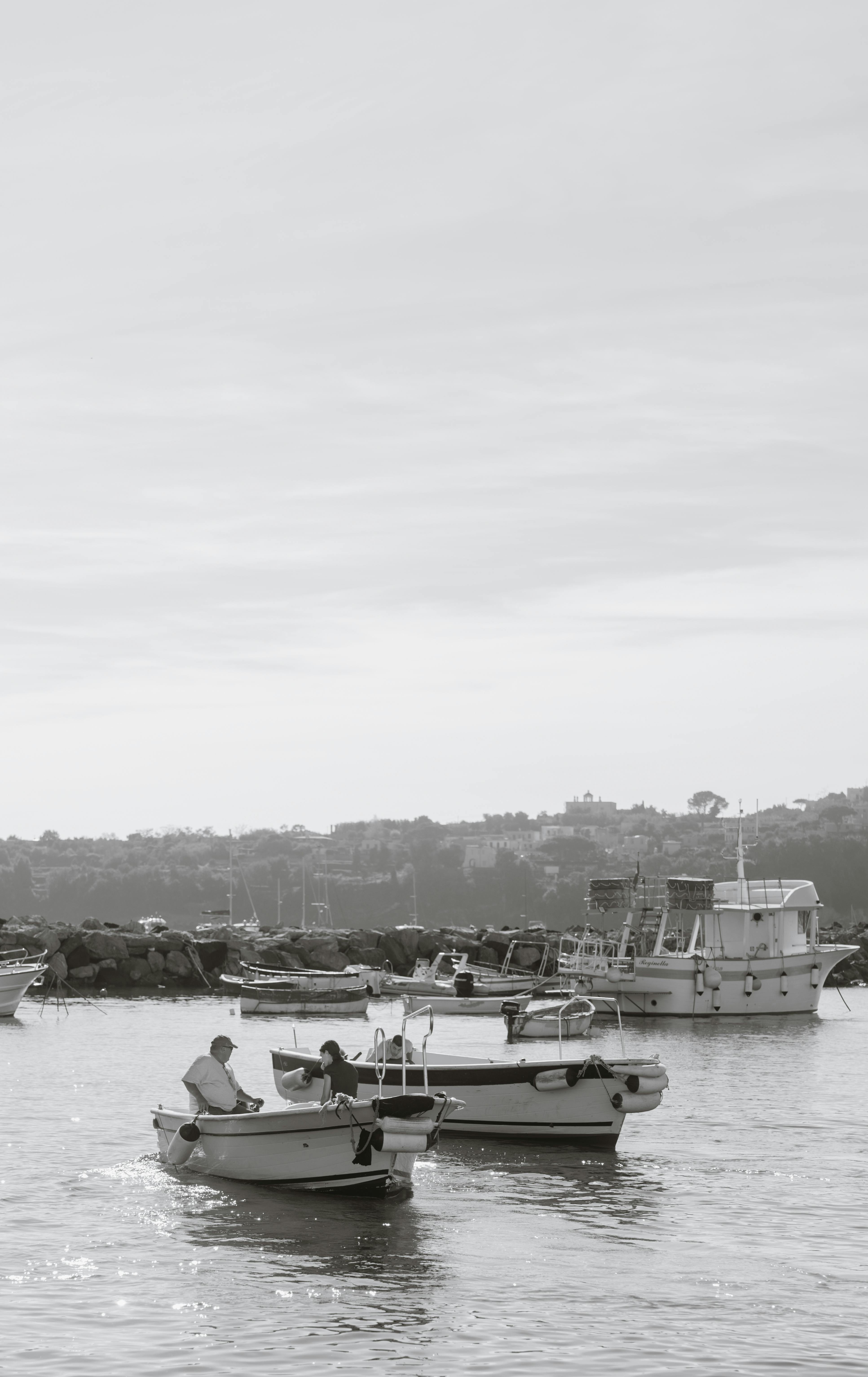 Безкоштовне Двоє людей ловлять рибу у спокійний день на невеликих човнах біля скелястого берега. стокове фото