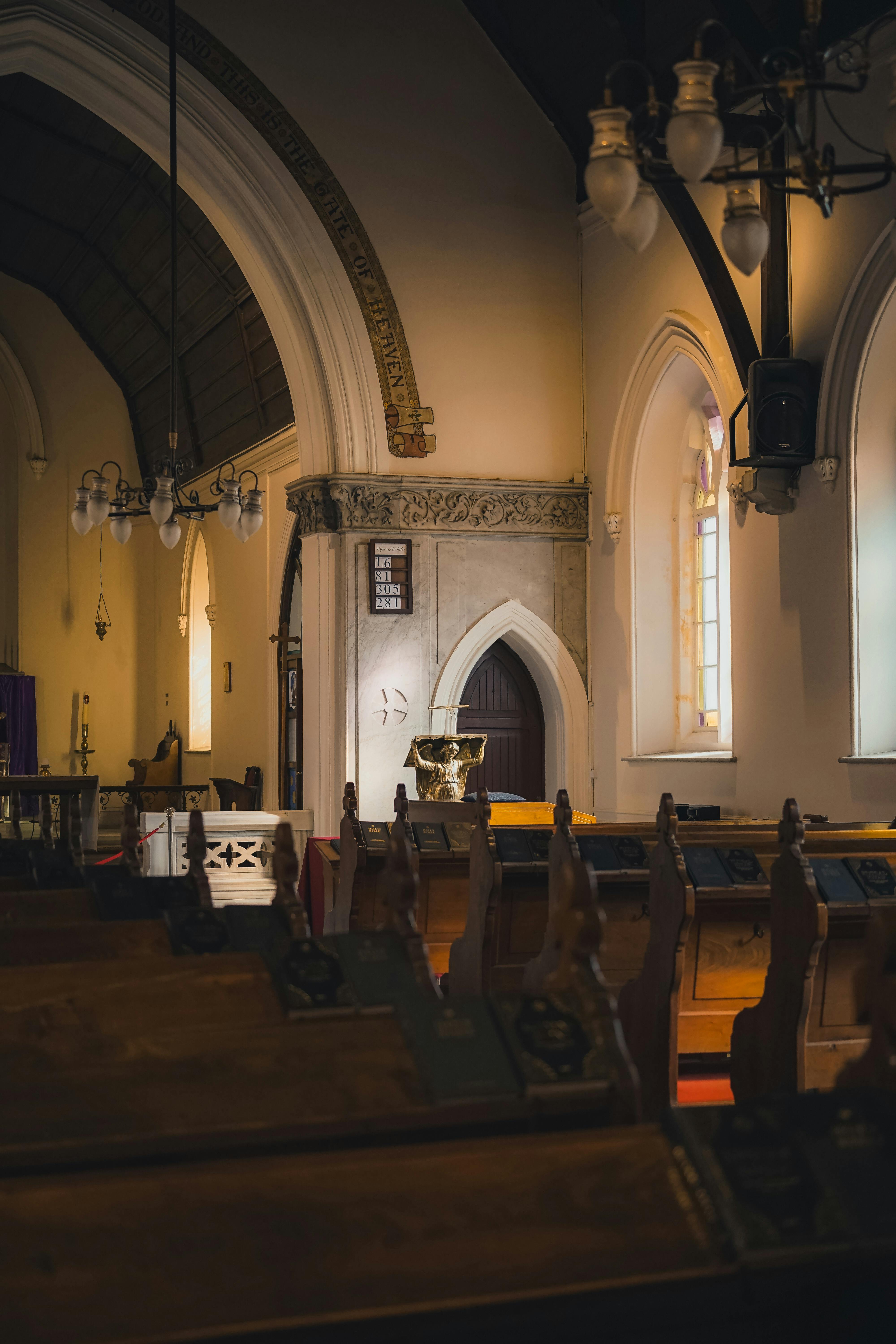 Free Beautiful gothic church interior with arched windows and pews in soft lighting. Stock Photo