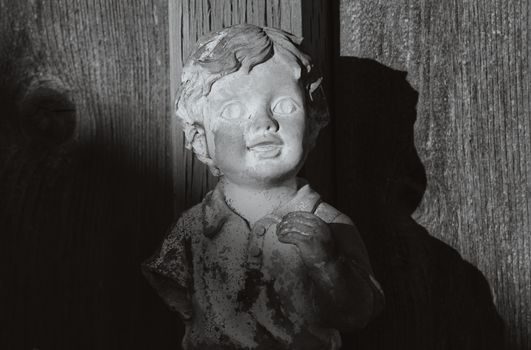 A black and white image of a child sculpture casting a shadow on a wooden surface.