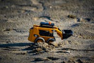 Toy Excavator in Sand on a Sunny Day