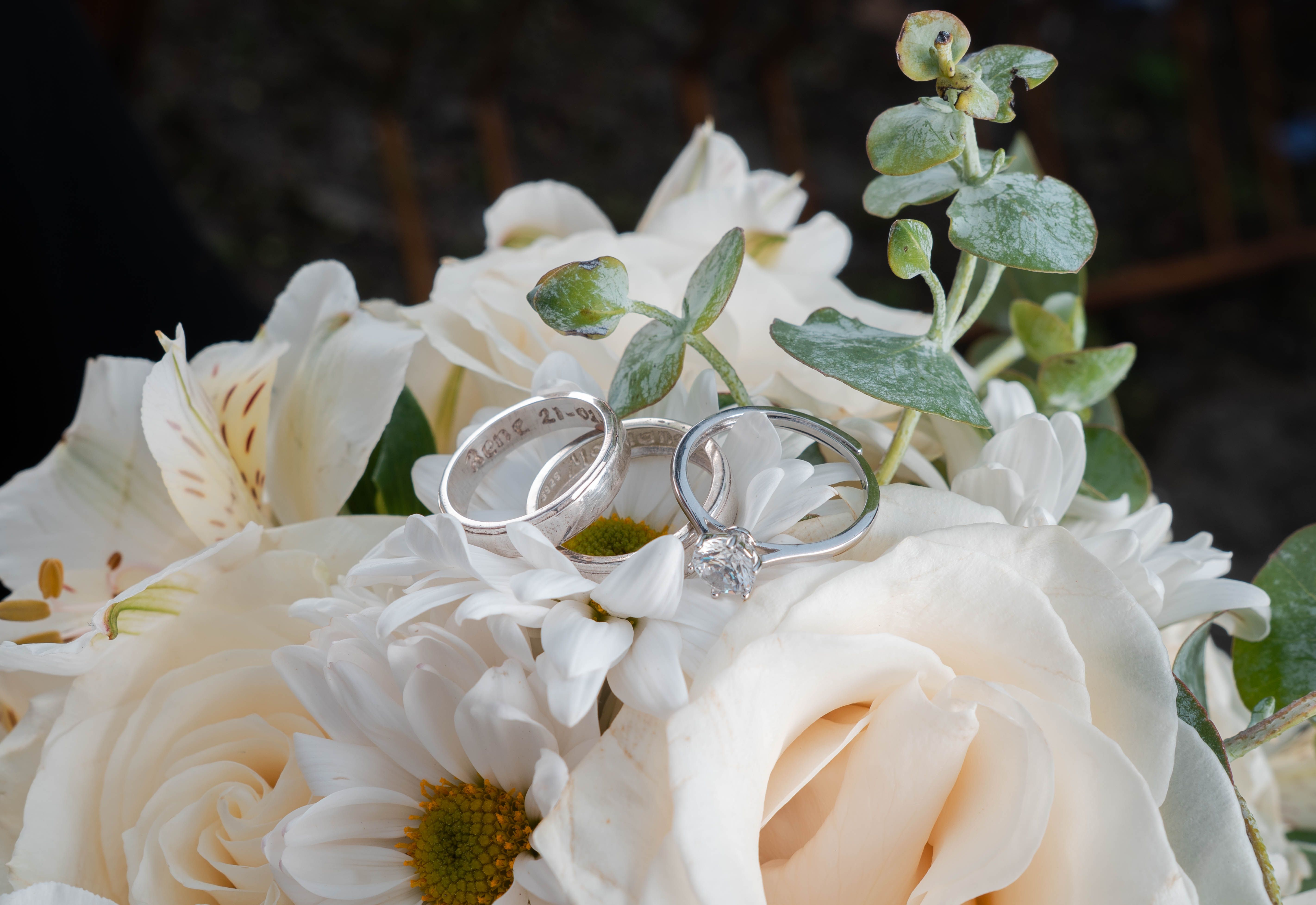 Wedding rings nestle into the texture of a pale floral bouquet.