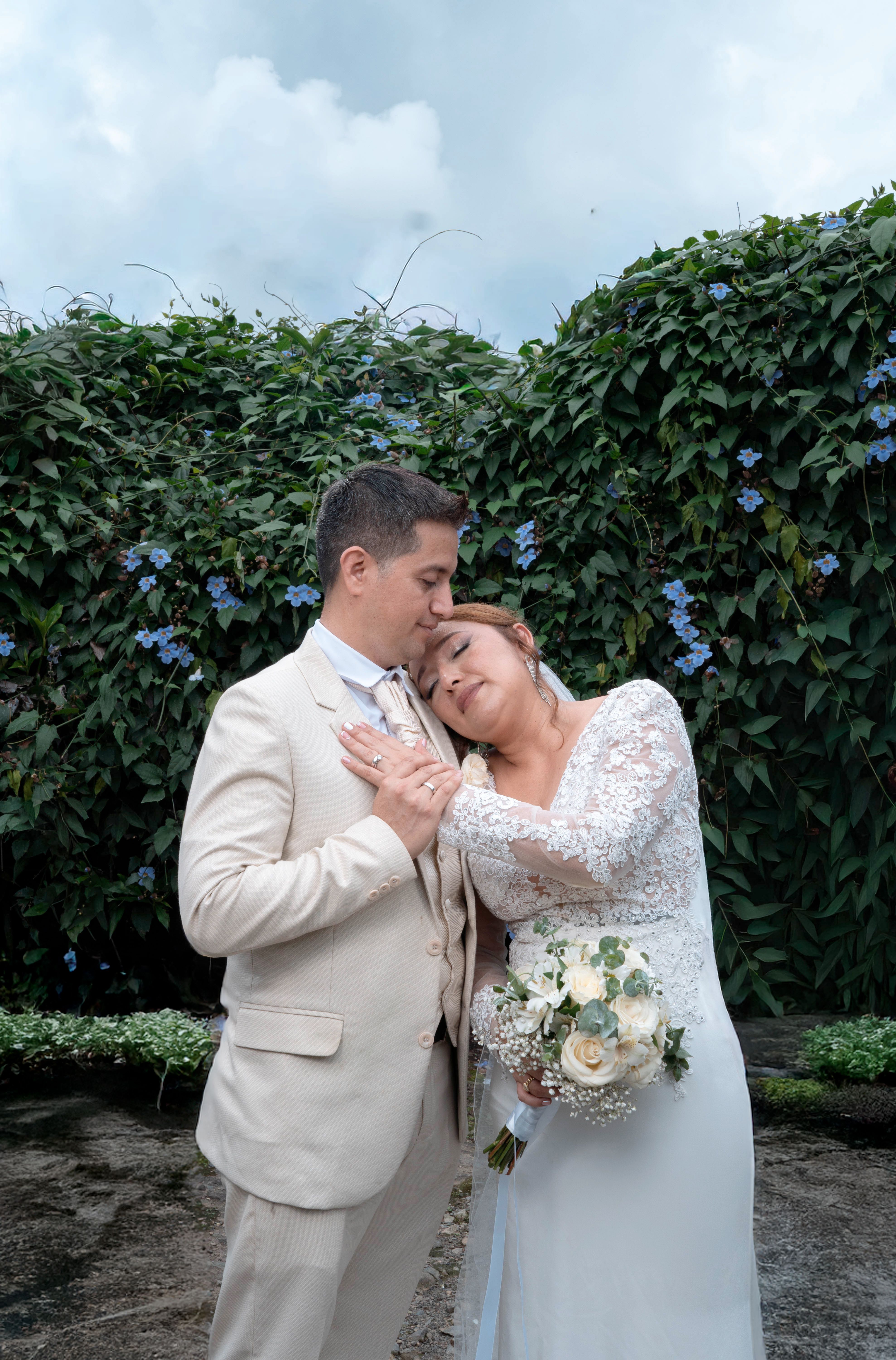 A loving wedding couple embrace in a lush Santo Domingo garden.