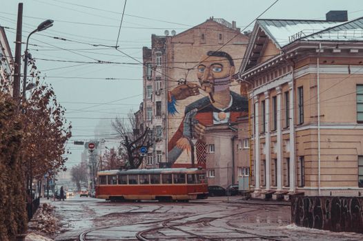 Vibrant tram scene in Kyiv, featuring artistic graffiti and historical architecture on a winter day.