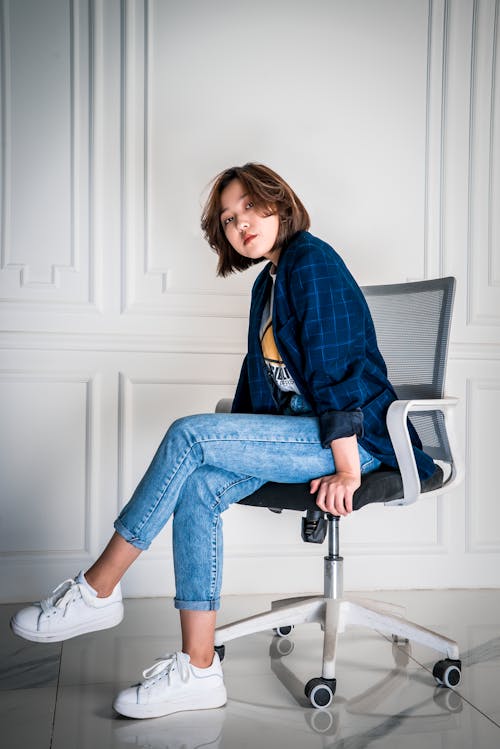 Woman In Blue Denim Jeans Sitting On A Chair