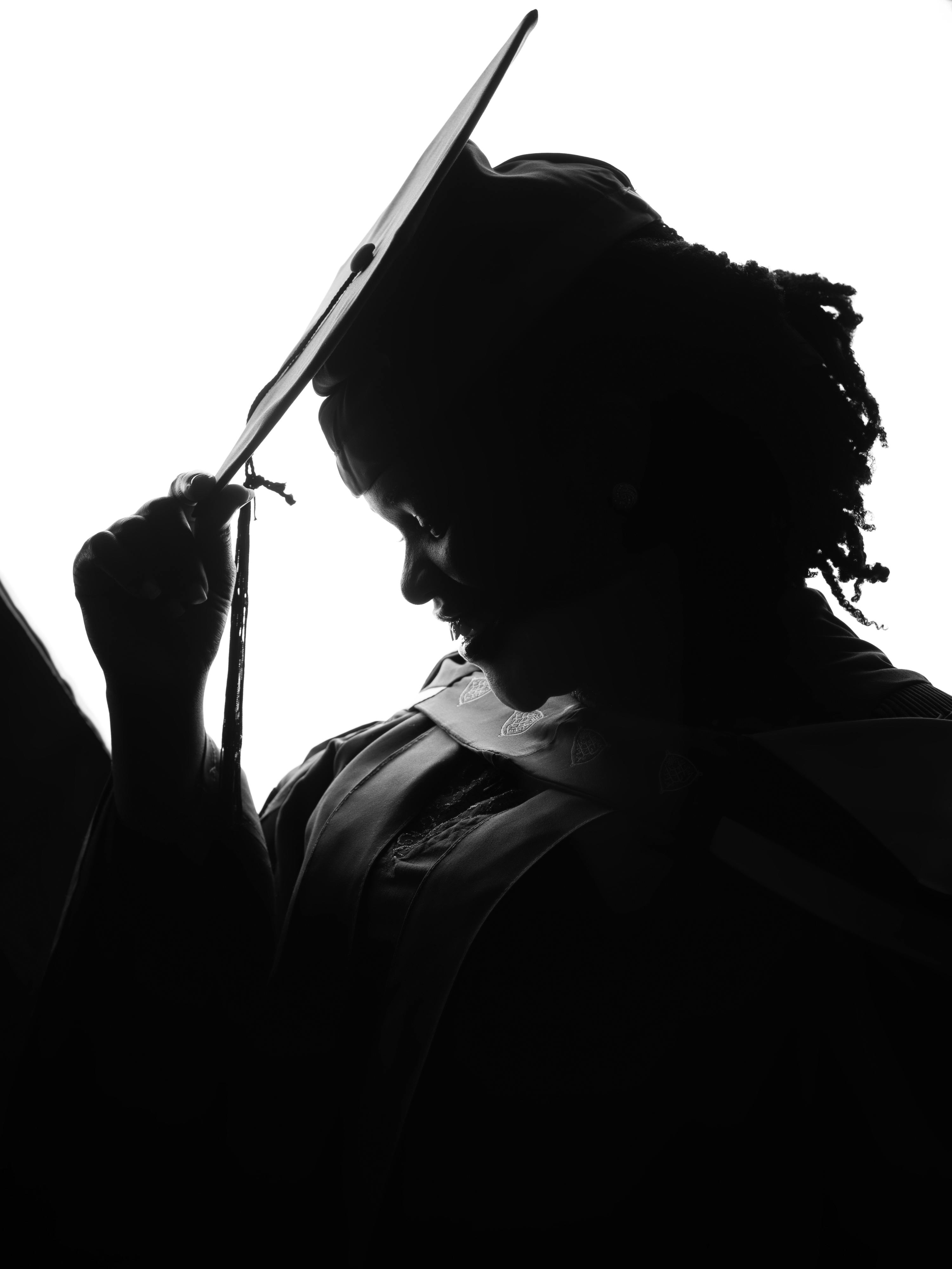 Free Elegant silhouette of a graduate adjusting their cap in profile. Stock Photo