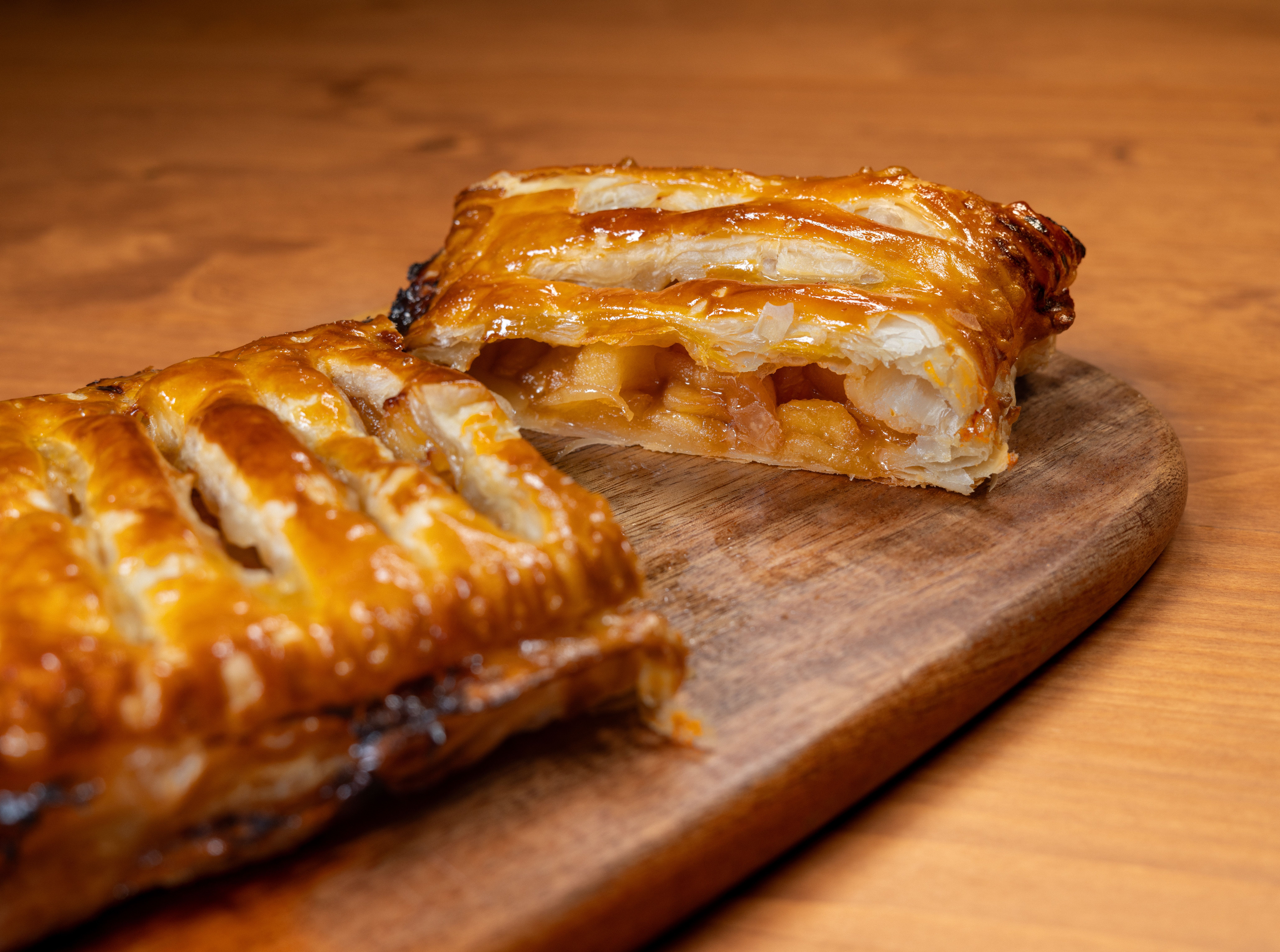 Delicious freshly baked apple strudel with golden flaky pastry on a wooden board.