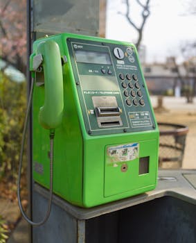 A vibrant green Japanese public telephone in an outdoor park setting, offering a nostalgic glimpse into retro communication.