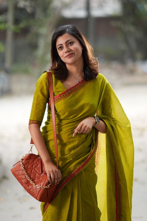 Free A woman in a green sari posing outdoors with a stylish orange handbag. Stock Photo
