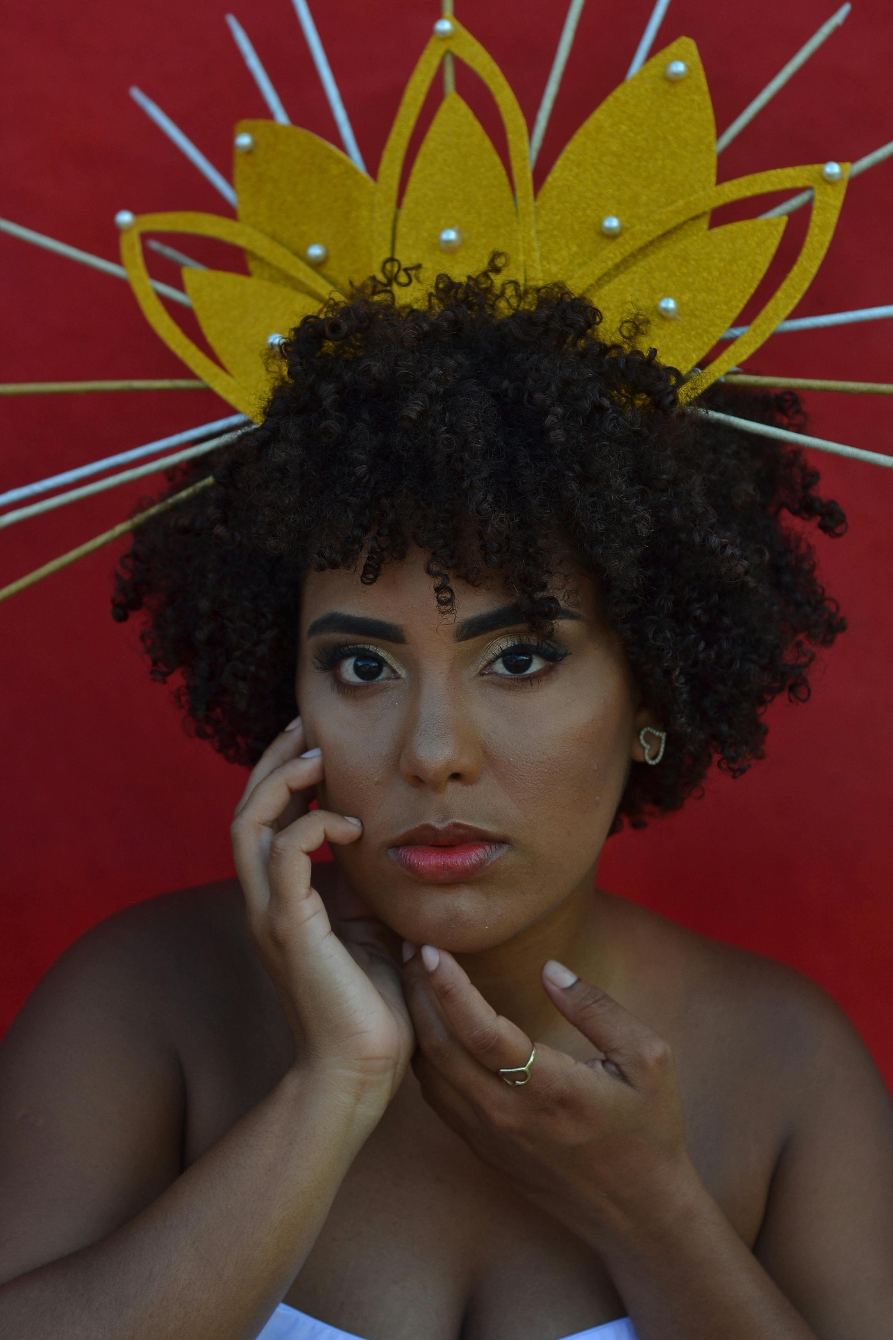 Close-up portrait of a woman wearing a decorative headpiece against a red background.