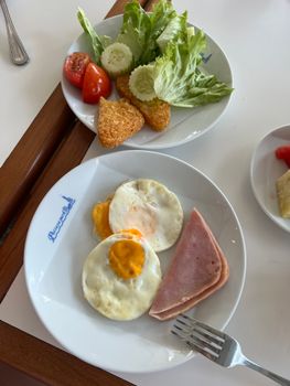 Enjoy a wholesome breakfast of eggs, ham, hashbrowns, and salad for a fresh start to your day.