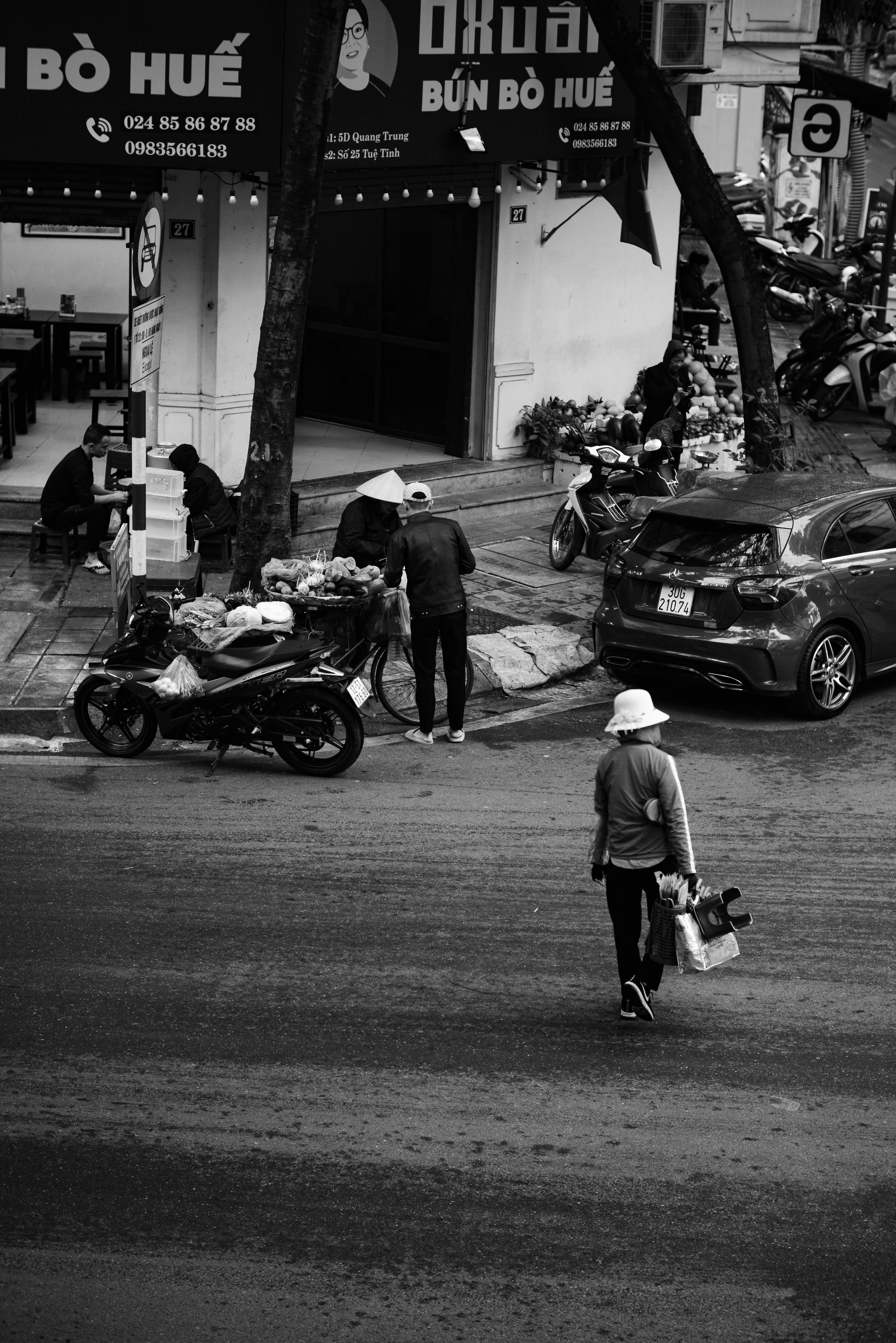 gratis Zwart-wit straatbeeld met voetgangers, motorfietsen en een Vietnamese winkelpui. Stockfoto