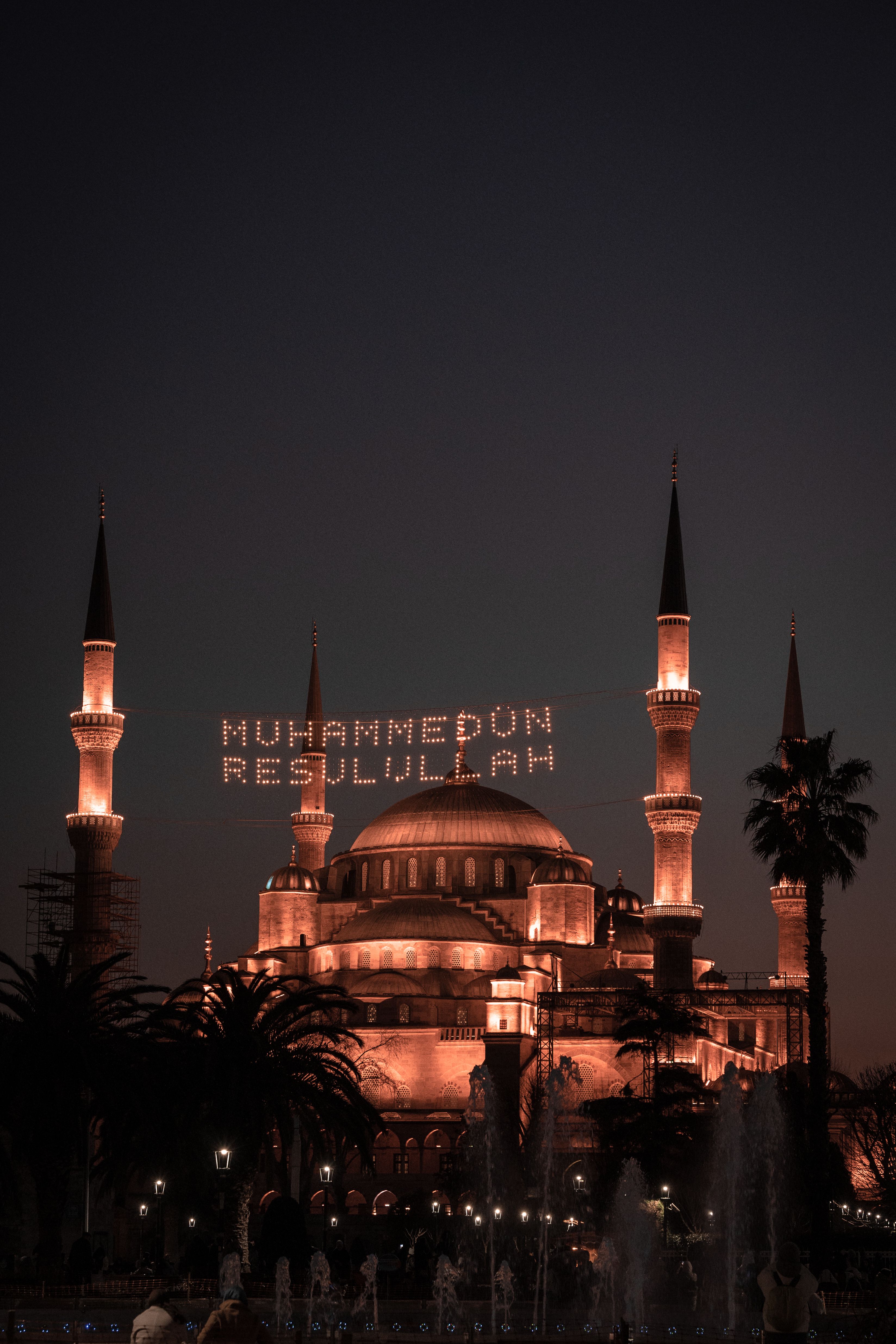 Evening view of the Blue Mosque in Istanbul with illuminated calligraphy in the sky.