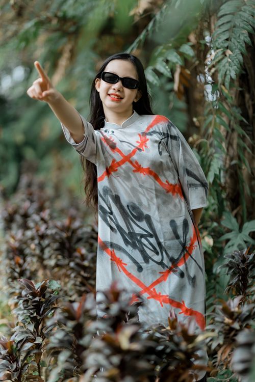 Free Trendy woman wearing sunglasses and graphic dress pointing outdoors. Stock Photo
