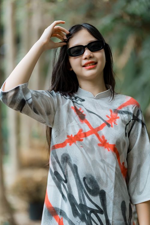 Free Stylish woman wearing sunglasses and a colorful tunic, enjoying a sunny day outdoors. Stock Photo