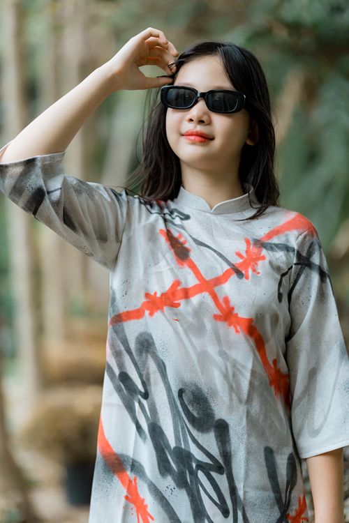 Free Trendy woman wearing sunglasses and an artistic dress while posing in a forest area. Stock Photo