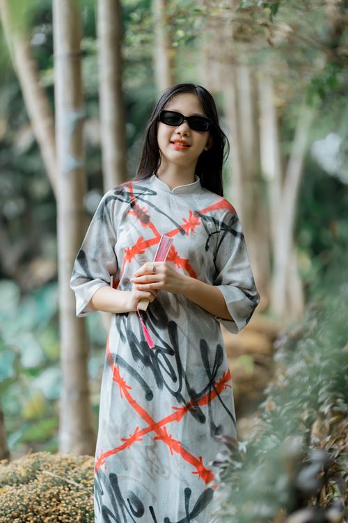 Free Fashionable woman in sunglasses and graffiti dress outdoors in a lush setting. Stock Photo
