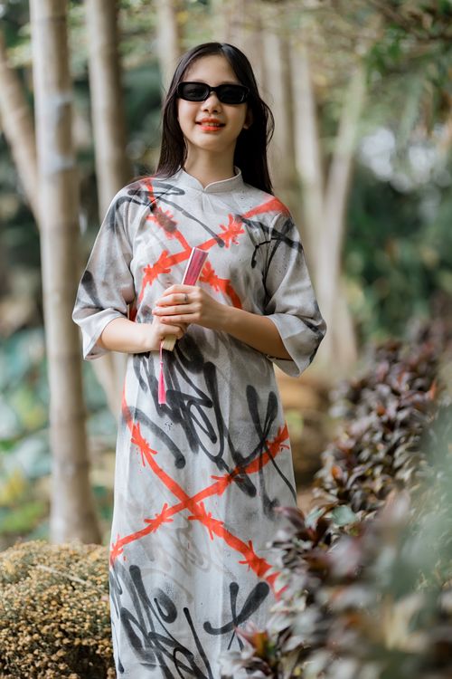 Free Stylish woman in artistic dress holding book, standing outdoors on a sunny day. Stock Photo