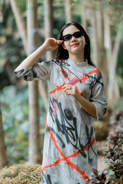 Free Fashionable woman in artistic dress holding a fan and wearing sunglasses outdoors. Stock Photo
