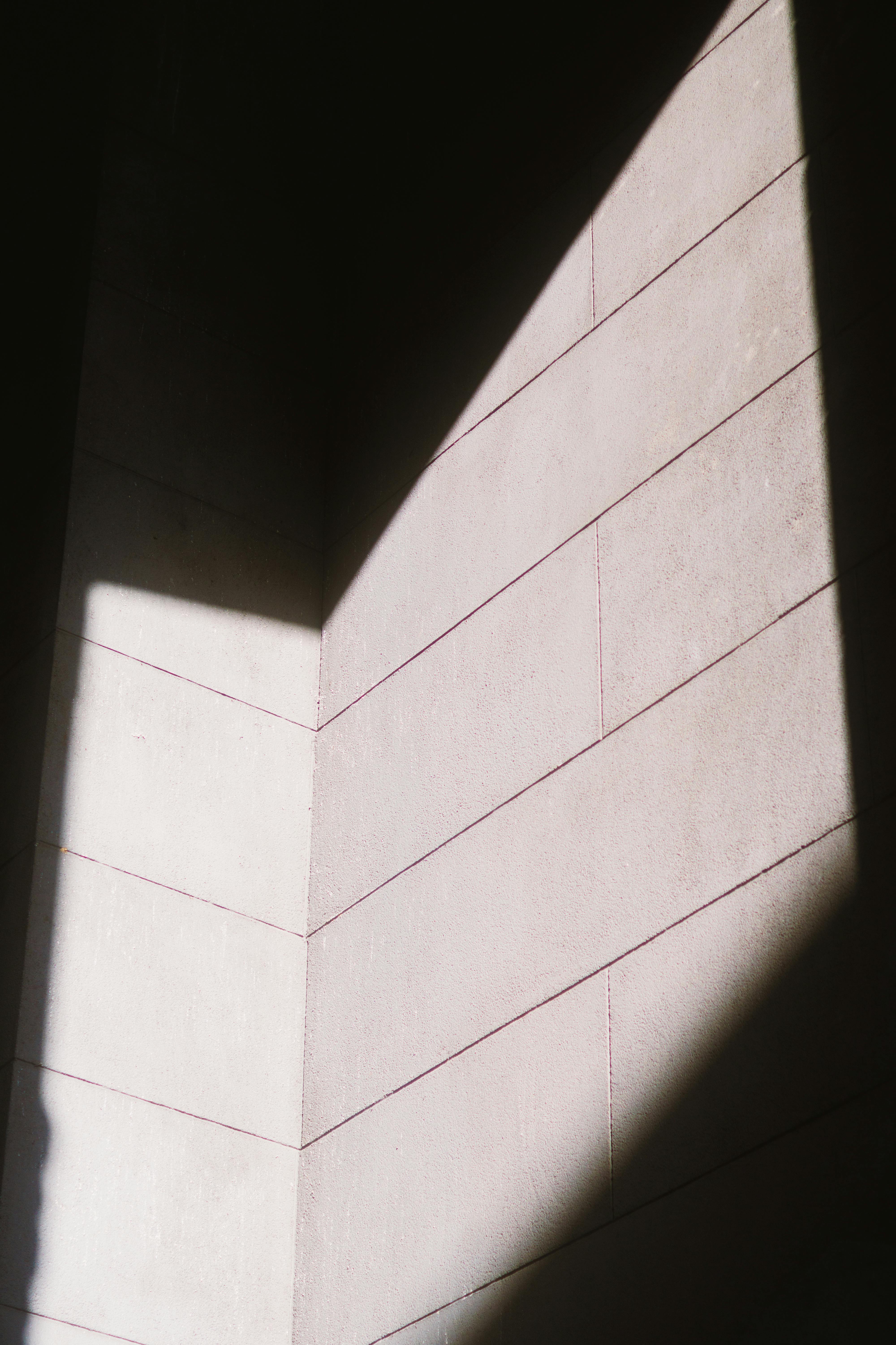 Gratis Una suggestiva immagine astratta di luce che proietta motivi geometrici su un muro di pietra. Foto a disposizione