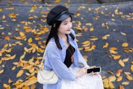 Young Woman in Stylish Outfit with Autumn Leaves