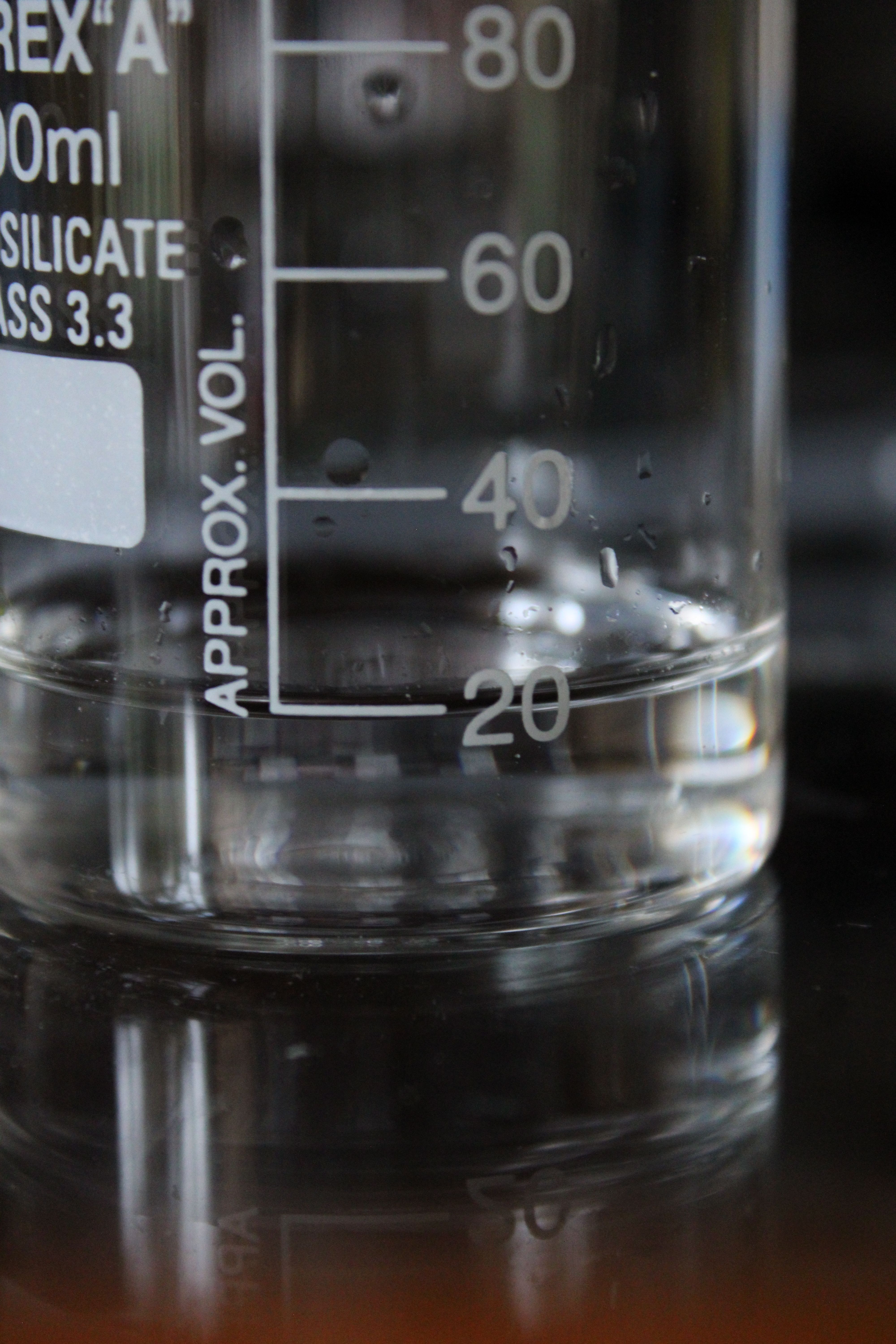 Detailed image of a laboratory beaker with visible volume markings, capturing water droplets.