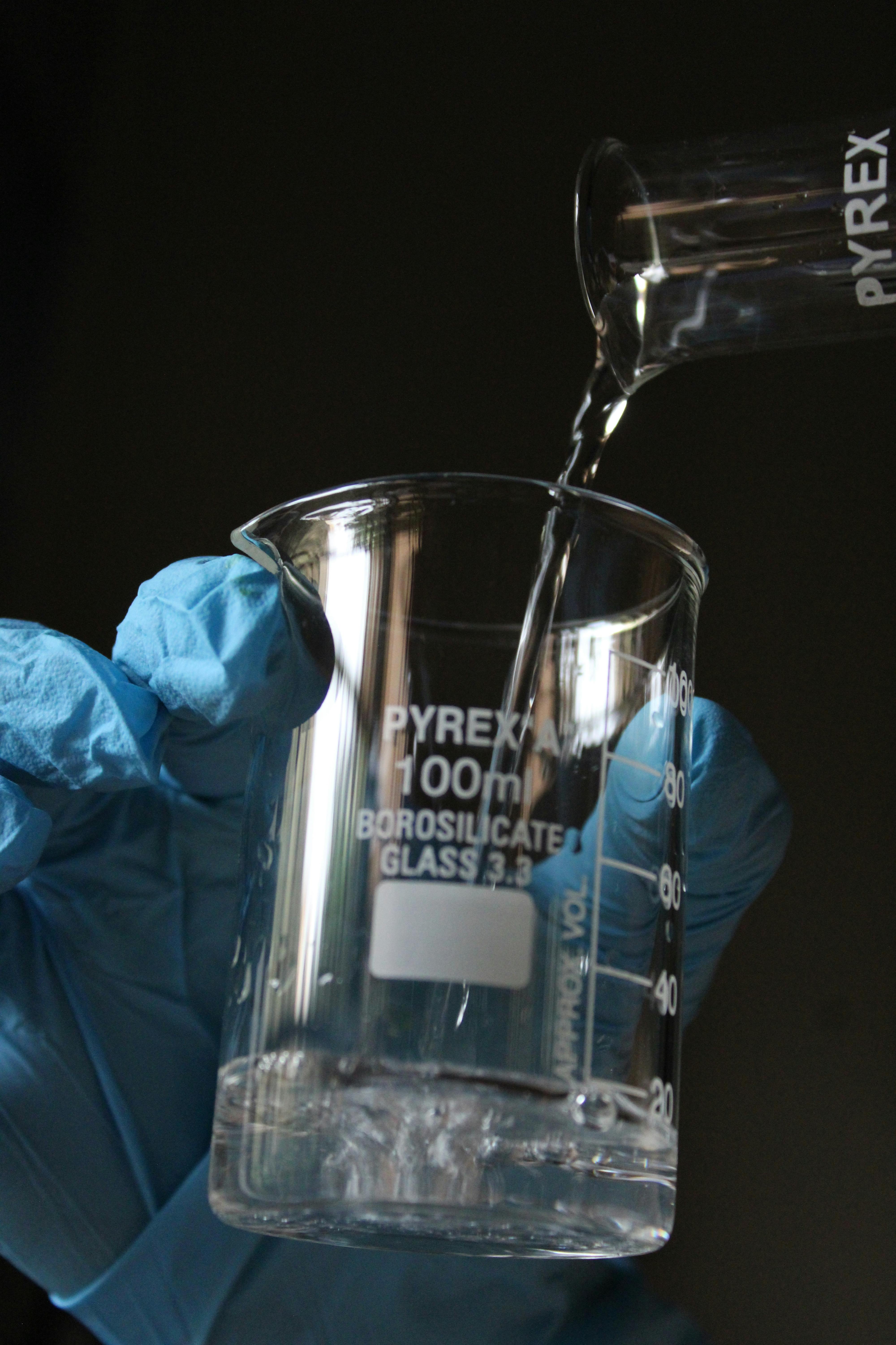 Close-up of liquid being poured into a Pyrex beaker. Ideal for lab and scientific themes.