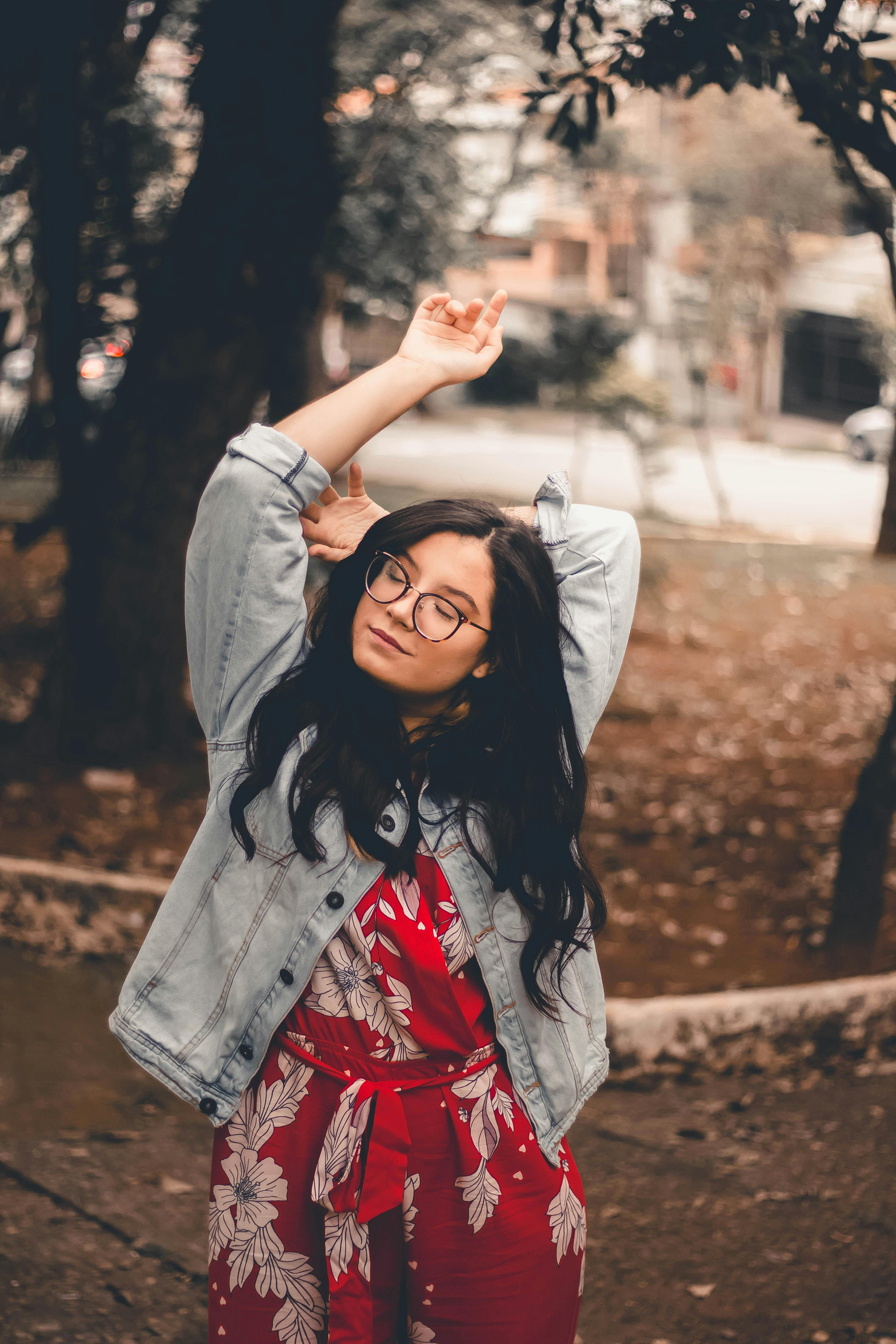 一位身穿红色花卉连衣裙和牛仔夹克的年轻女子正在户外享受休闲时光