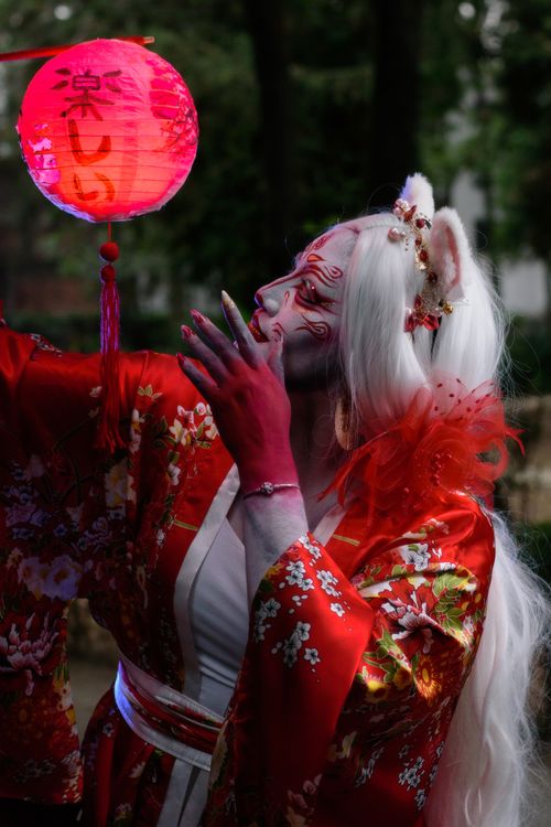Free Cosplayer in traditional attire holding a lantern at night in a magical setting. Stock Photo