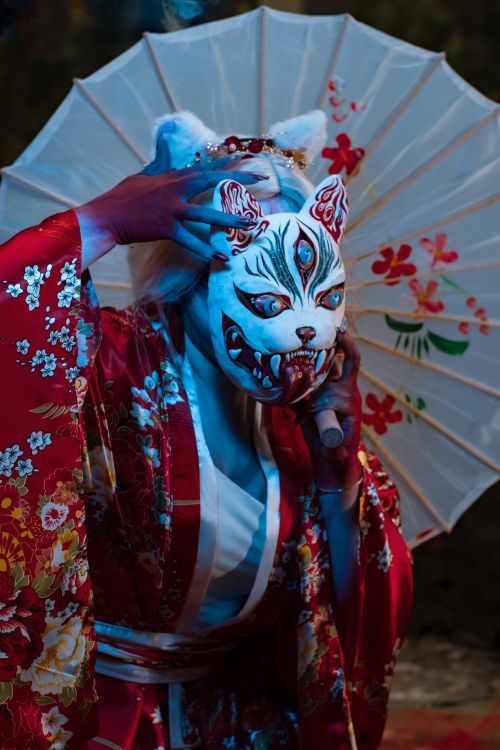 Free Geisha in floral kimono performing traditional dance with Japanese mask. Stock Photo