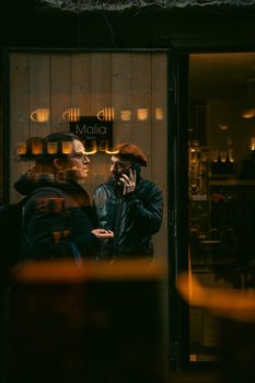 Moody street photo with reflections in Naples, showing people in a shopfront light.