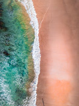 Stunning aerial shot depicting a beach's shoreline with turquoise waves meeting soft sand.