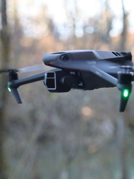 A modern drone flies outdoors, showcasing technology against a blurred natural background.