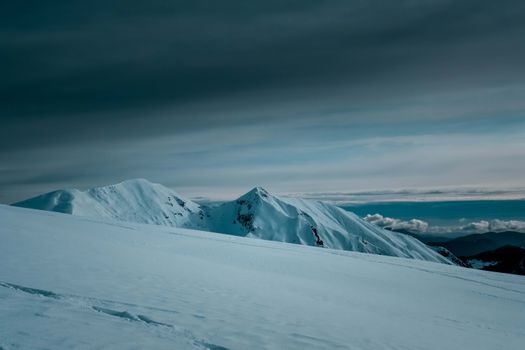 Captivating view of snow-covered mountains under a dramatic cloudy sky.