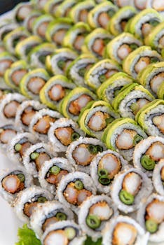 A close-up of assorted sushi rolls with vibrant veggies and seafood, freshly prepared and artfully arranged.
