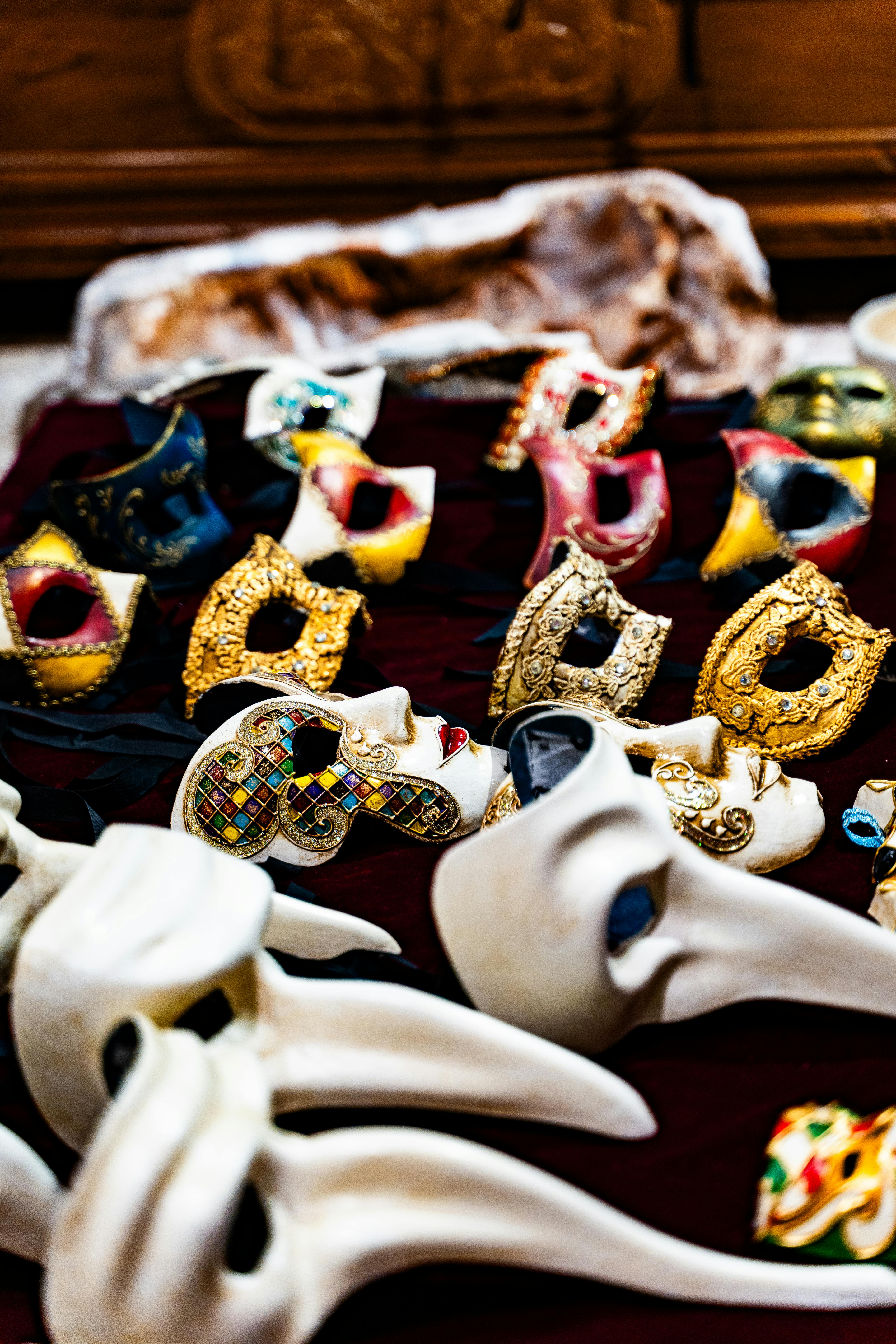 Free A vibrant collection of Venetian masks with intricate designs and colors, showcased in a market setting. Stock Photo