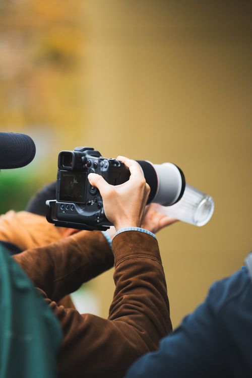 Free Close-up of a photographer using a camera with a long lens outdoors, focusing on a distant subject. Stock Photo