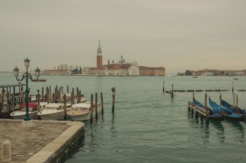 Free Peaceful view of Venice's canals with gondolas and historic buildings in the background. Stock Photo