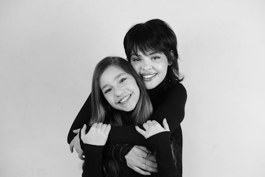 A heartwarming black and white portrait capturing two young girls sharing a joyful embrace.