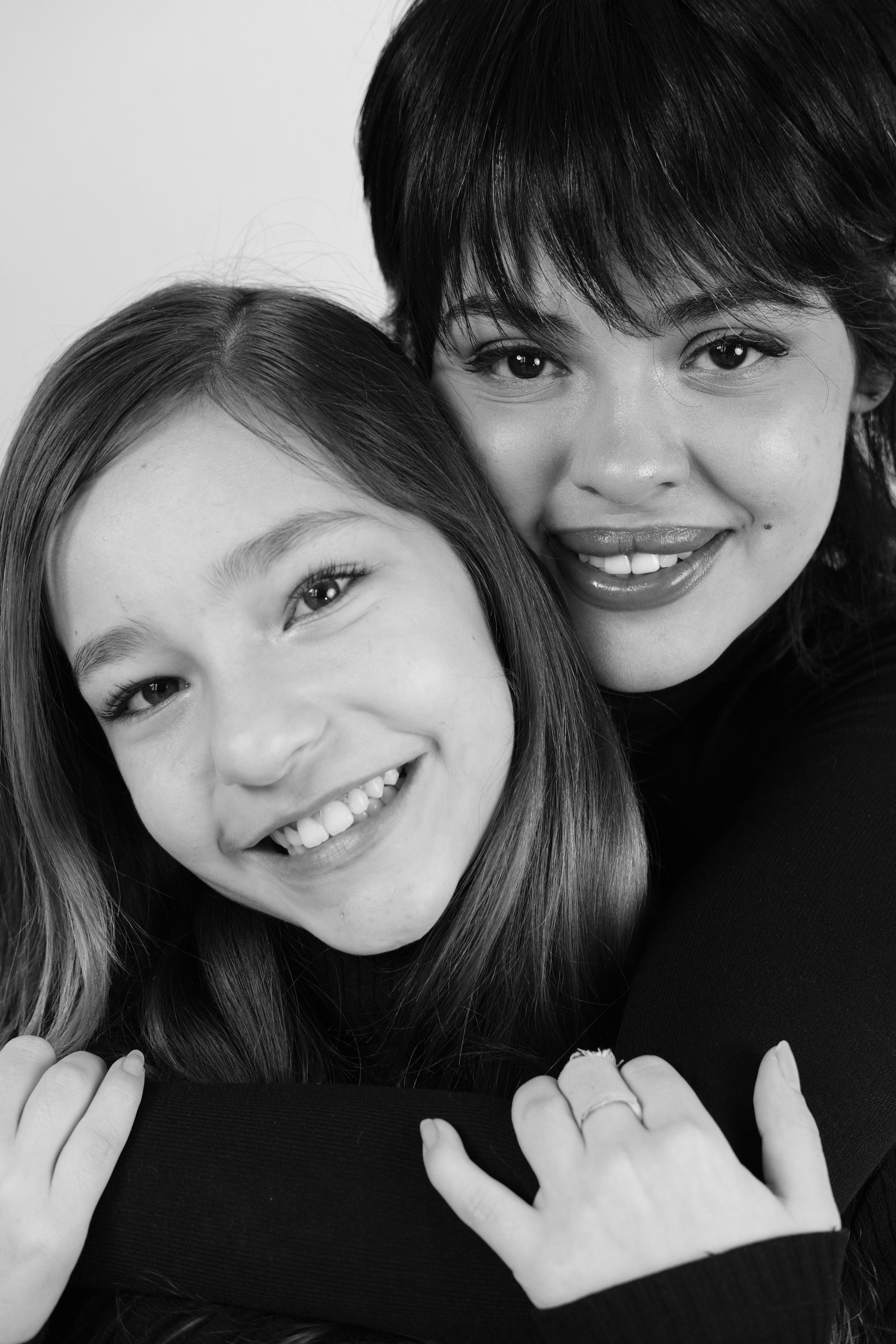 Close-up black and white portrait of a mother and daughter smiling warmly at the camera.
