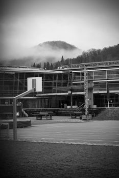 Deserted basketball court with a misty mountain backdrop and modern architecture in black and white.