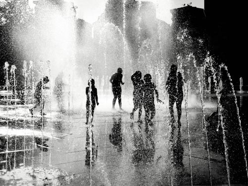 Free Children and adults enjoy a water fountain in İstanbul, captured in black and white. Stock Photo