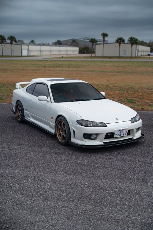 Free White sports car at an outdoor parking area with a cloudy sky backdrop. Stock Photo